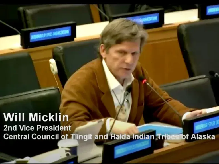 La imagen muestra a un hombre sentado en un escritorio con un micrófono frente a él. Lecturas de texto: Will Micklin 2nd Vicepresidente del Consejo Central de Tribus Indias de Tlingit y Haida de Alaska